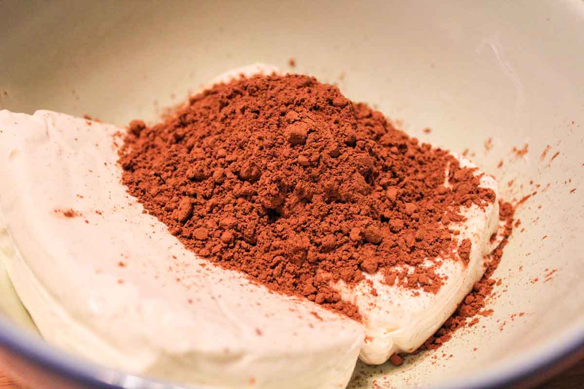 cocoa powder on top of cream cheese in a bowl