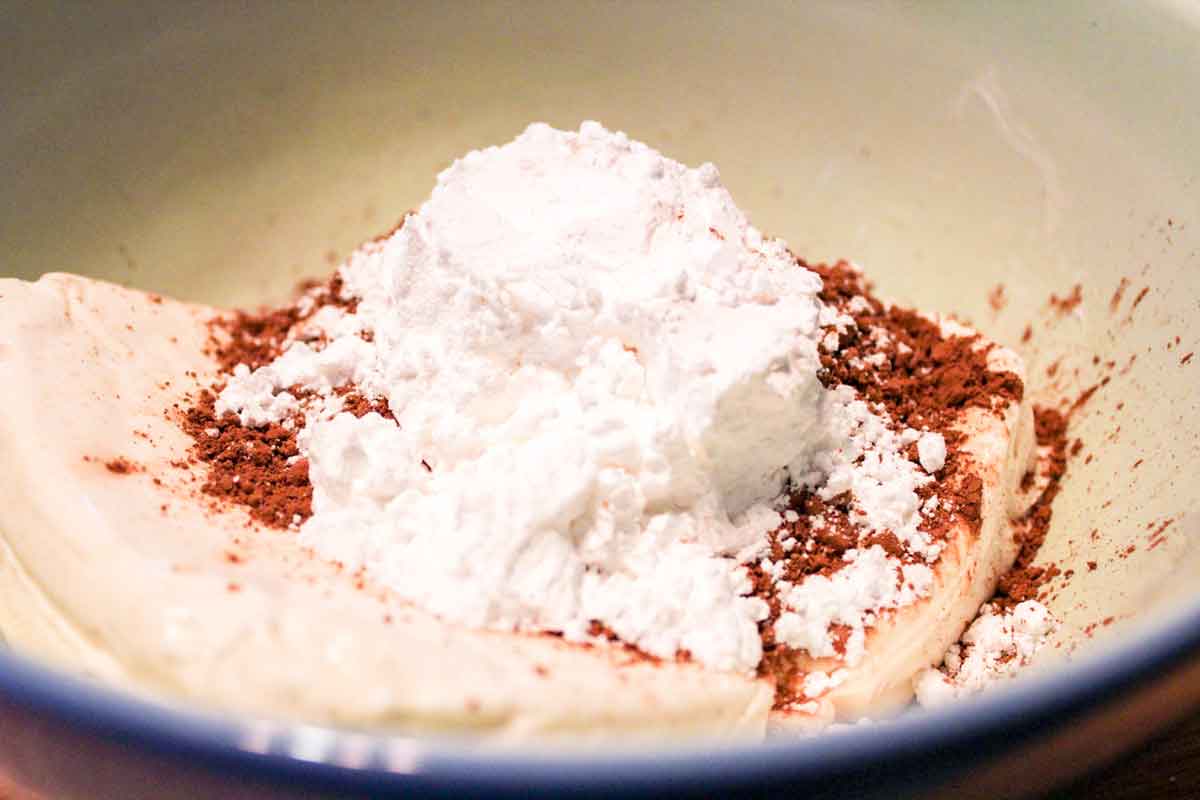 powdered sugar and cocoa powder on top of cream cheese in a bowl