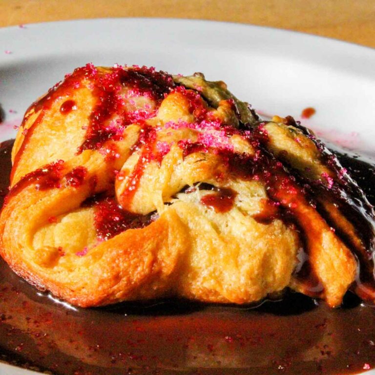 Chocolate Puff Pastry Dripping in Chocolate Sauce on a White Plate - Featured Image