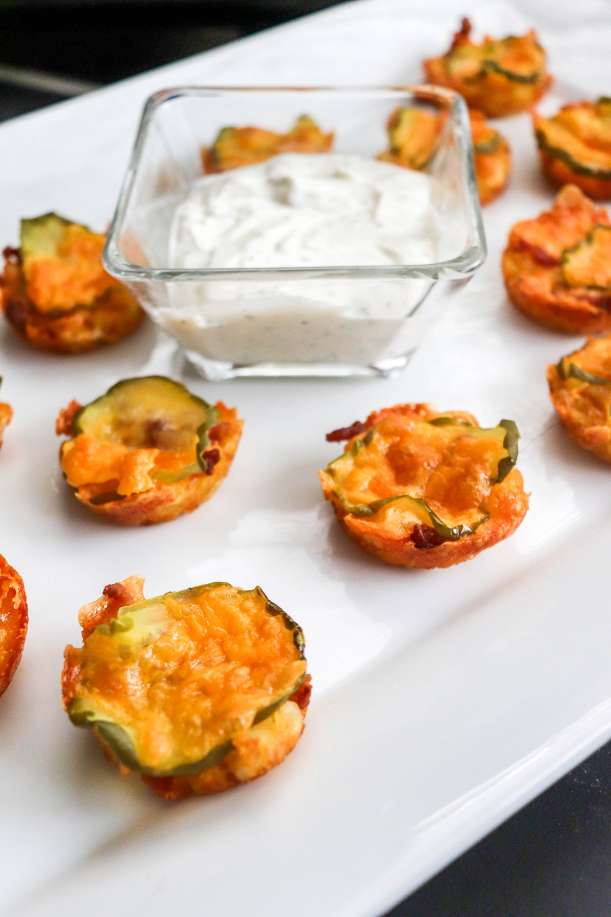 Fried Pickle Chips on a white platter with ranch dressing