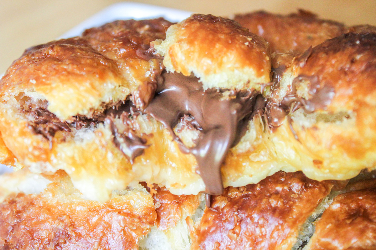 Extreme close up of melted chocolate hazelnut spread between two slices of croissant