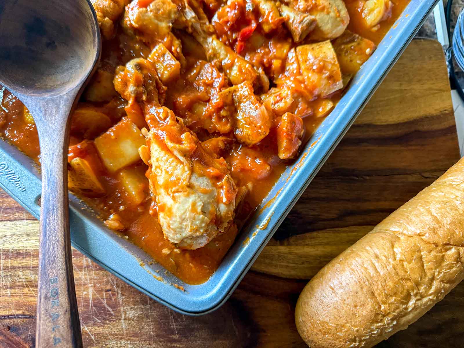 Portuguese chicken and potatoes in a baking pan with fresh bread