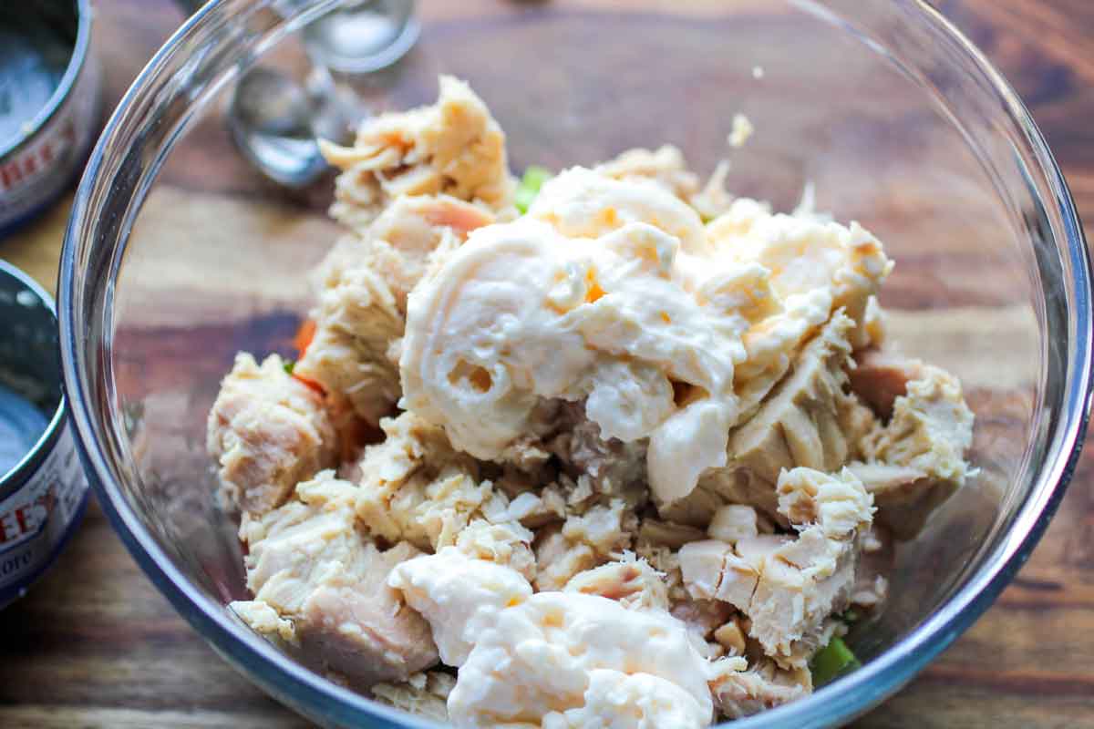 Mayo added to a bowl with tuna and veggies