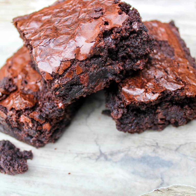 Three Coconut Chocolate Brownies stacked on parchment paper - Featured Image
